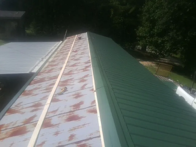 Old rusted panels beside newly installed green metal roofing — Wind Damage Roof Repair by Roofing Brothers in Cromwell