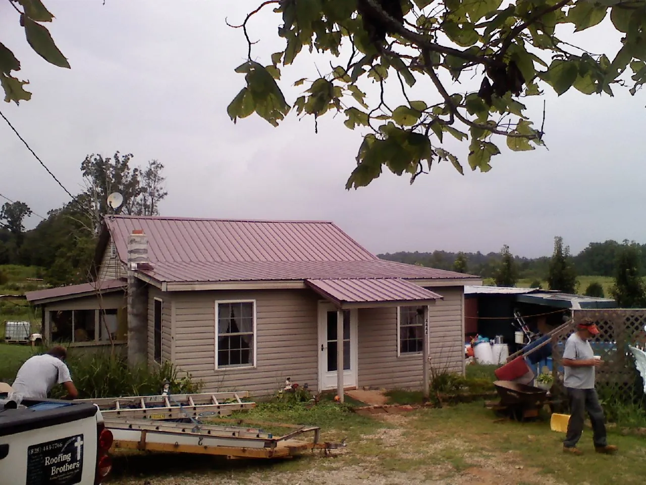 Crew finishing a mauve metal roof on a small farmhouse in Cromwell