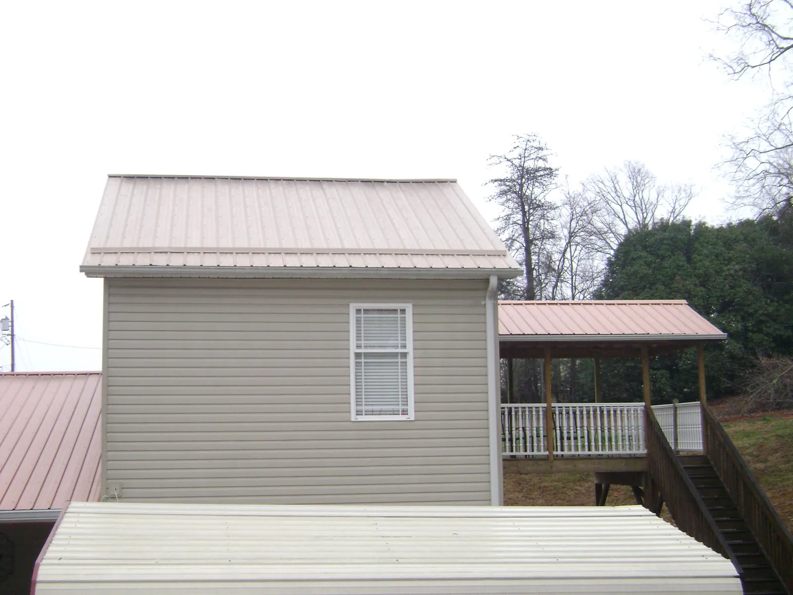 Tan metal roofs on a two story addition and attached porch, from a Roof Replacement job in Cromwell