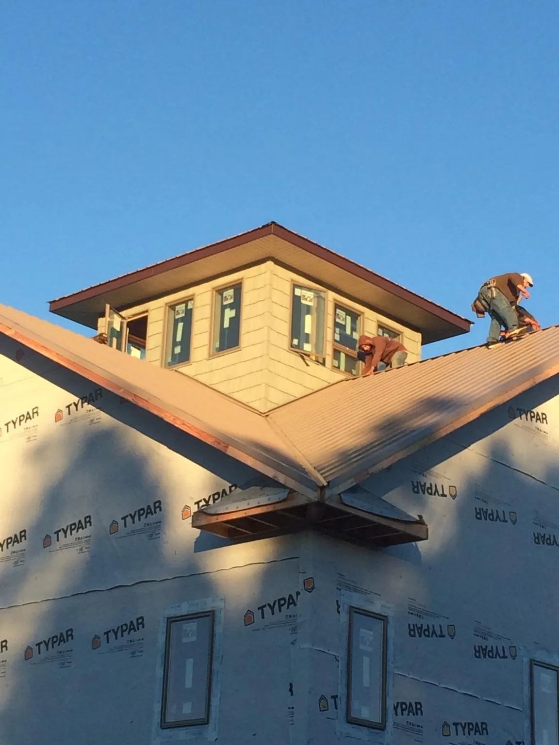 Roofers working around a rooftop cupola on a new metal roof at sunset — Roof Waterproofing in Cromwell by Roofing Brothers
